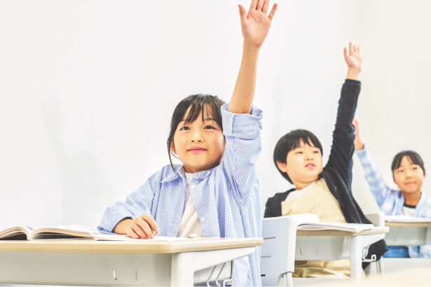 授業中に手を挙げる小学生たち